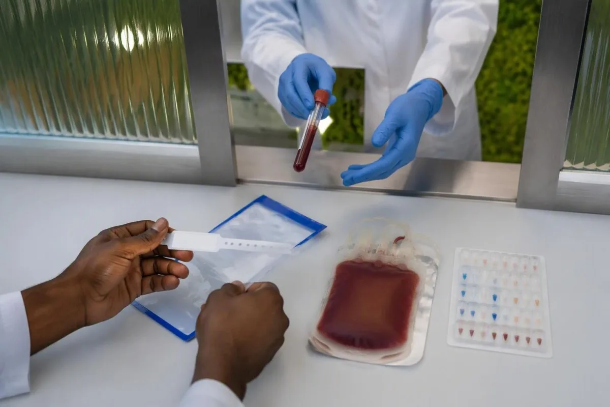 Crossmatch test sample handover with identity checks and a sealed donor segment at the laboratory hatch